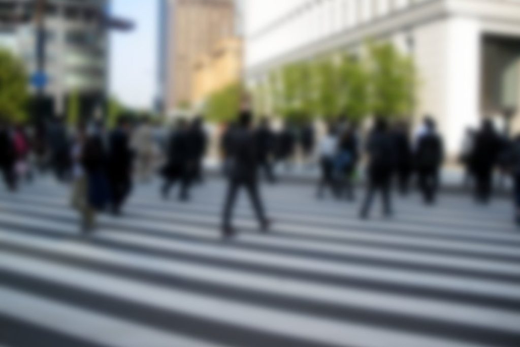 朝の丸の内の横断歩道を渡る通勤の人々（人物はぼかしている）