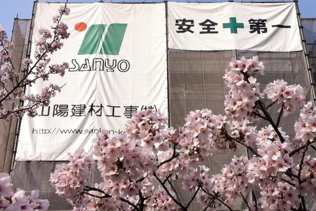 桜の枝の向こうに見える「安全第一」の看板