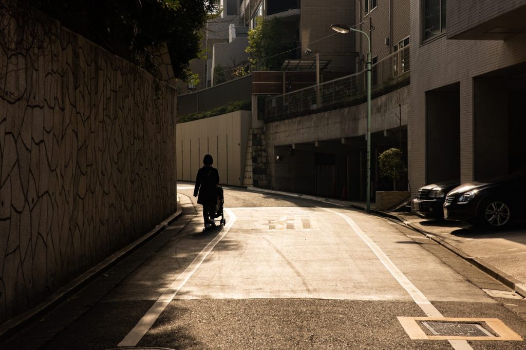 ベビーカーを押して坂道を歩く人の後ろ姿